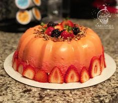 a cake with strawberries and blackberries on top is sitting on a countertop