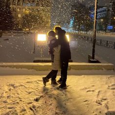 two people standing in the snow with their arms around each other