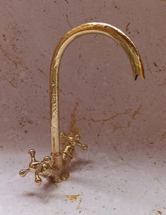 a brass faucet with a frog on it's side and a long curved handle