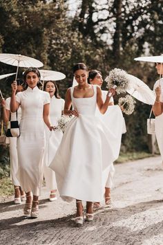 the bridesmaids are walking down the road with umbrellas in their hands as they walk towards the camera