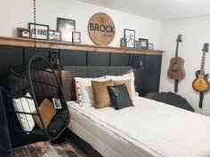 a bed room with a neatly made bed and some guitars on the wall above it