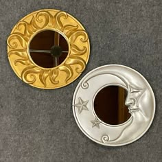 two mirrors sitting on the floor next to each other, one with a gold and silver design