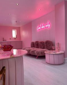 a room with pink walls and furniture in the center is lit up by neon lights