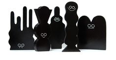 five black wooden figures with faces and eyes on them, all in the same shape