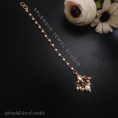 a flower and some pearls on a black surface with the words splendid jewel studio written in gold