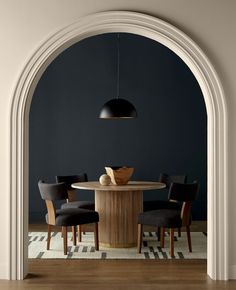 a dining room with an arch leading into the kitchen