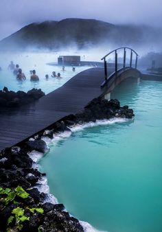 several people are in the water near a dock and some hot springs with blue water