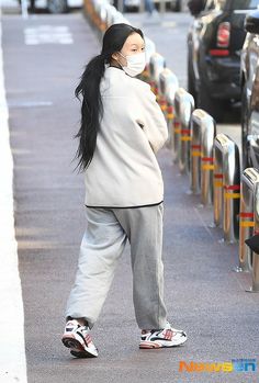 a woman wearing a face mask walking down the street with her hand on her hip