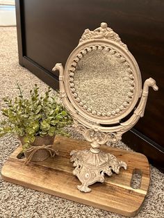 a mirror sitting on top of a wooden board next to a potted plant