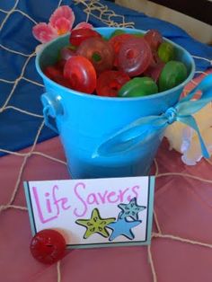 a blue bucket filled with gummy bears next to a sign that says life saver