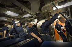 men in uniform are standing on the deck of a ship and one man is holding something up