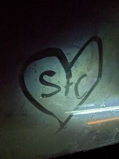 graffiti on the side of a bus window in the dark with light coming through it