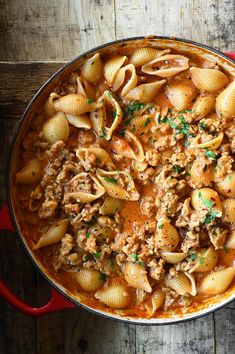 a red pot filled with pasta and meat