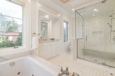 a large white bathroom with a walk in shower next to a bathtub and sink