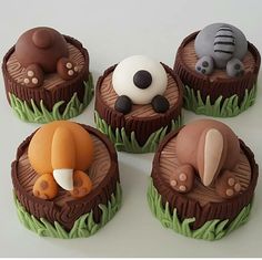 four cupcakes with animals on them sitting in the grass