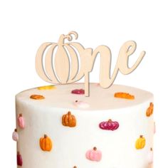 a white cake topped with a wooden one sign and lots of small pumpkins on it