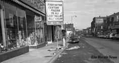 an old black and white photo of a movie theater sign on the side of a street