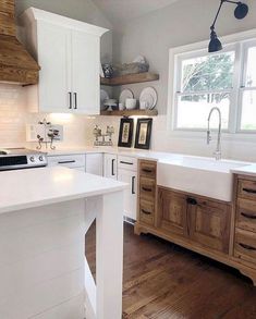 a kitchen with wooden floors and white cabinets, an island countertop and sink area