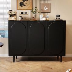 a black cabinet in the corner of a room with pictures on the wall above it