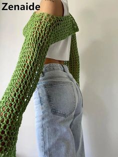 the woman is wearing a green knitted scarf over her shoulder and has one hand on her hip