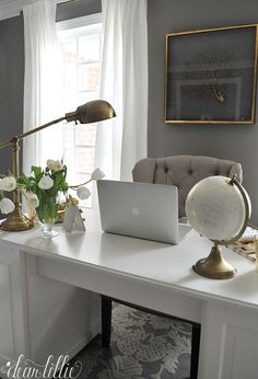 a white desk topped with a laptop computer sitting next to a window covered in curtains