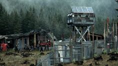 a group of people standing in front of a forest next to a building with a solar panel on top