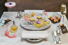 a table topped with plates and glasses filled with desserts next to wine glasses on top of a marble counter