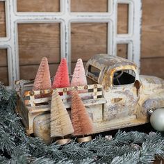 an old toy truck with christmas trees in the bed and behind it is a white ornament