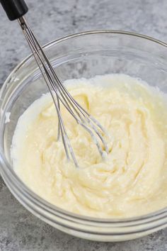 a glass bowl filled with cream and two whisks in it on a table