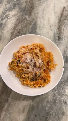 a white plate topped with pasta covered in sauce and parmesan cheese on top