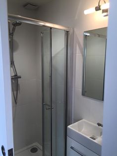 a bathroom with a shower, sink and mirror