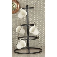 three tiered coffee cup holder with four cups on it and a clock in the background