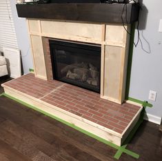 a brick fireplace is being installed in a living room with wood flooring and white walls