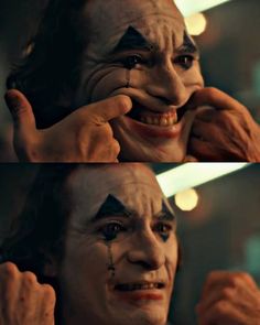 the joker with his face painted to look like he is smiling and pointing at something