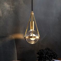 a modern light fixture hanging from a ceiling in a living room with dark walls and furniture