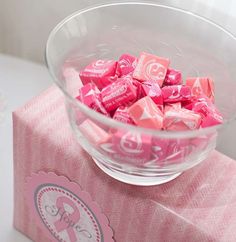 a bowl filled with pink candy sitting on top of a table next to a box