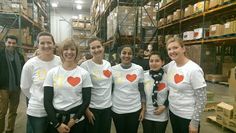 a group of people standing next to each other wearing t - shirts with hearts on them