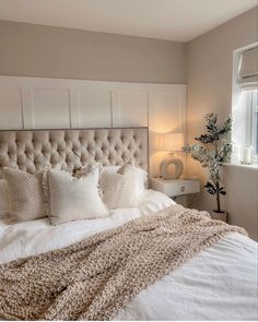 a bed with white sheets and pillows next to a window