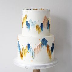 a three tiered white cake with multicolored icing