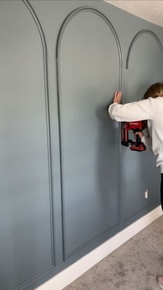 a woman working on a wall with a driller