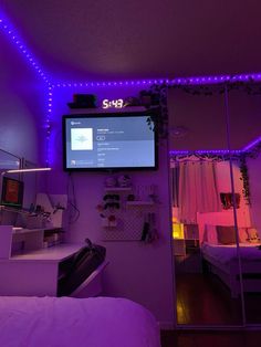 a bedroom with purple lighting and a flat screen tv mounted to the wall above it