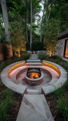 an outdoor fire pit surrounded by stone steps and trees at night with lights on the sides