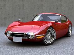 a red sports car parked in front of a concrete wall