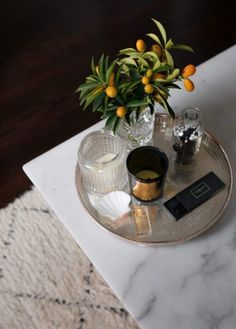 a marble table topped with a vase filled with oranges and other things on top of it