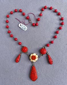 "Made of carved cinnabar and set in sterling silver, this wonderfully distinctive, Arts and crafts style choker is made in a floral design which makes it quite unique looking.  Made of sterling silver with a spring ring clasp.  The choker length necklace measures just under 18\" from end to end. The central piece is 5/8\" wide x 2 1/8\" long.  I see no damage of any kind. The metal has light use marks. The clasp works as it should and holds well. I consider this to be in excellent vintage condit Red Carved Jewelry For Wedding, Red Carved Vintage Jewelry, Carved Red Vintage Jewelry, Arts And Crafts Style, Length Necklace, Long I, Choker Necklaces, Flower Necklace, Spring Rings