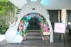 the entrance to a building decorated with fake flowers and plants in front of an arch