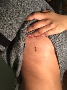 a woman with a small cross tattoo on her left side ribcading the lower part of her stomach