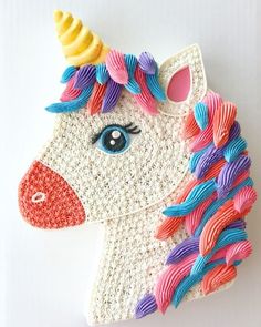 a crocheted unicorn brooch with colorful manes on it's head