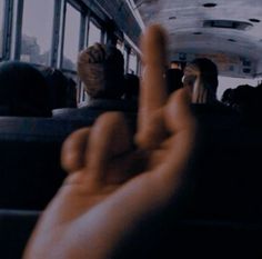 two fingers up in the air as people sit on a bus and look out the window