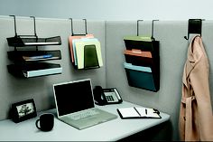 an office cubicle with a laptop, phone and other items hanging on the wall